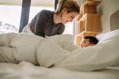 Young Mother And Her Son Playing Together On The Bed At Home Woman