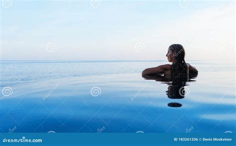Woman At Edge Of Infinity Swimming Pool With Sea View Stock Photo