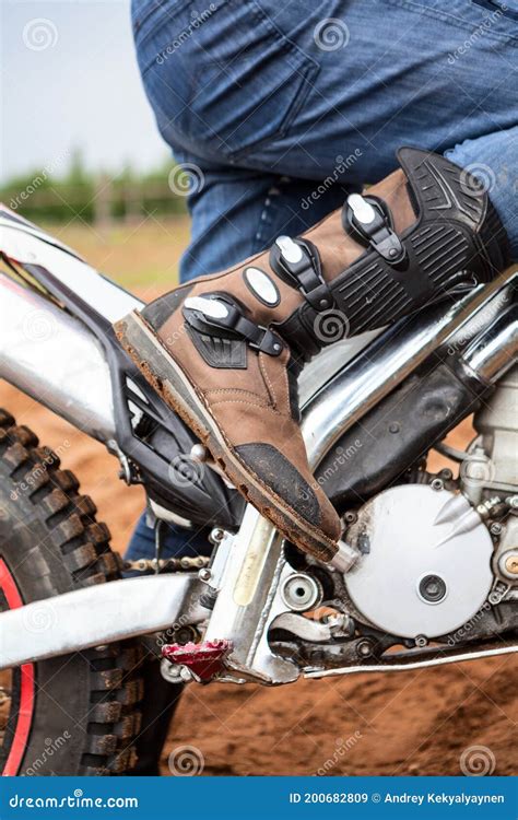 Rider With Motocross Boot Standing On Dirt Motorcycle Foot Is On Kick