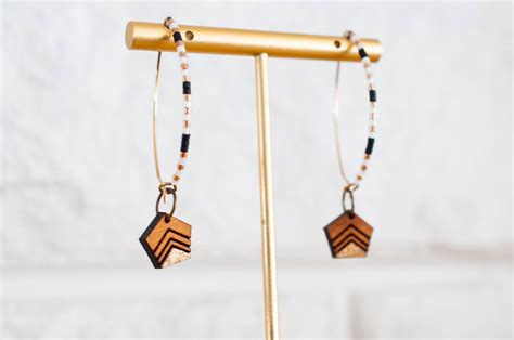 A Pair Of Wooden Earrings Hanging From A Metal Stand On A White Wall
