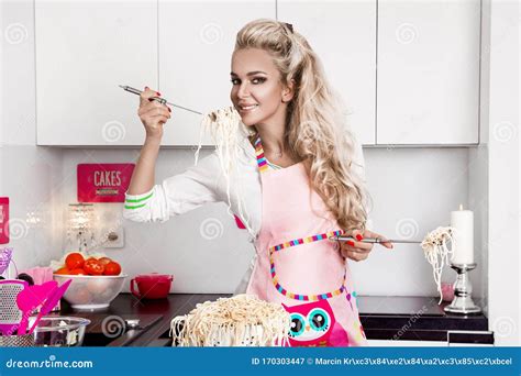 Beautiful Young Woman In Chef Apron Is Mixing Batter Looking At Camera