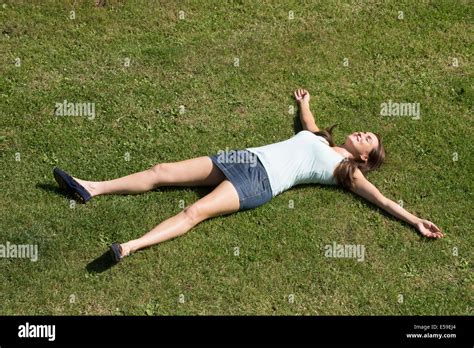 Young Woman Wearing A Mini Skirt Laying On Grass With Arms And Legs