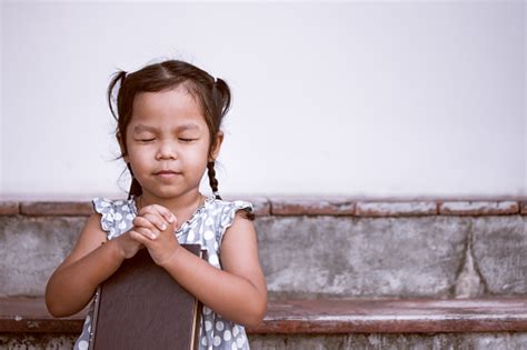 Cute Asian Little Girl Closed Her Eyes And Folded Her Hand In Prayer On