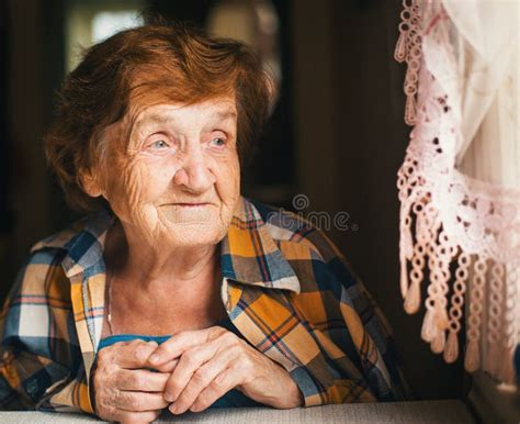 An Elderly Happy Woman Is Looking Out The Window Stock Image Image