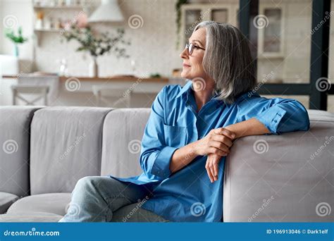 Calm Relaxed Mature Older Woman Relaxing Sitting On Couch At Home