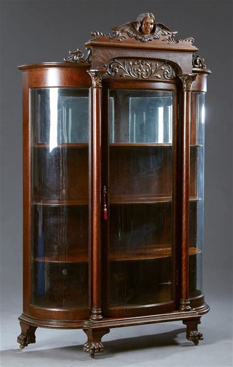 A curio cabinet is a specialised type of display case, made predominantly of glass with a metal or wood framework, for presenting collections of curios, like figurines or other interesting objects that invoke curiosity, and perhaps share a common theme. American Carved Oak Curved Glass Curio Cabinet, late 19th c.