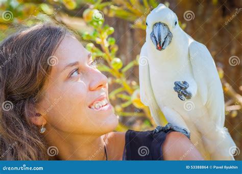Young Woman With White Parrot Sitting On Her Shoulder Stock Photo