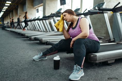 Tired Overweight Woman Sitting On Treadmill In Gym Stock Photo