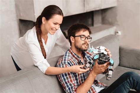 the couple plays with the robot a rhinoceros the guy sits on the couch and holds the robot in