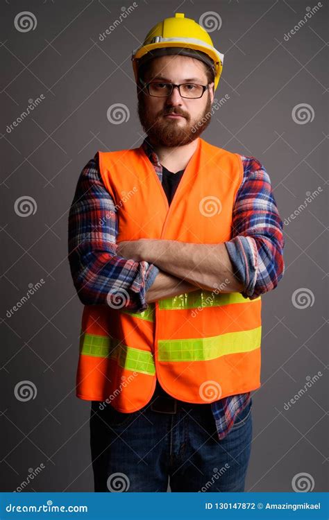 Young Bearded Man Construction Worker Against Gray Background Stock