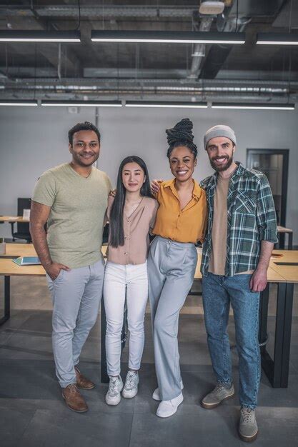 Premium Photo Four Interracial Young People Standing Hugging At Office