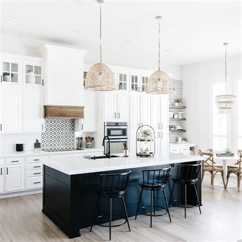 It's a fantastic color scheme that creates a beautiful and white cabinets contrasted with black countertops and black appliances and then all tied together with a metallic blue backsplash. black shiplap island and white cabinets with touches of natural wood and woven pendants over the ...