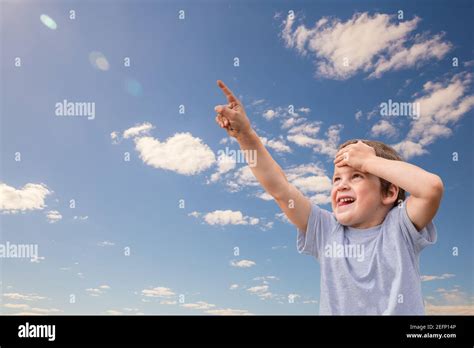 Little Happy Child Boy Looking Up At Sky And Points Up With His Finger