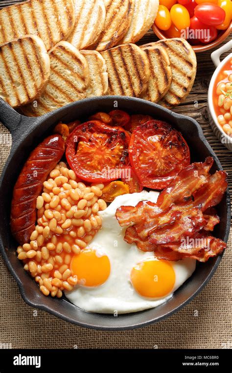 English Breakfast With Sausages Grilled Tomatoes Egg Bacon And Beans On Frying Pan Stock