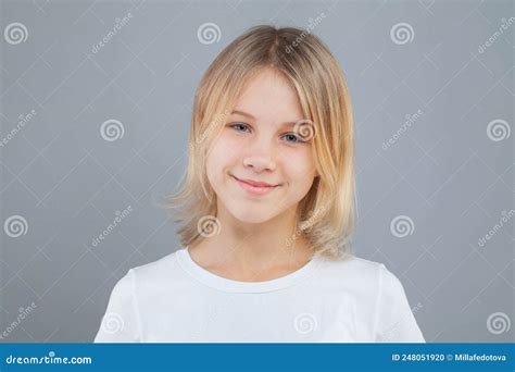Happy Little Blonde Kid Girl In White T Shirt On Gray Background