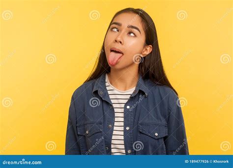 Portrait Of Funny Dumb Crazy Girl In Denim Shirt Showing Tongue Out And