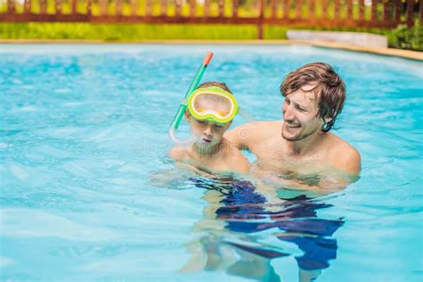 Dad And Son In Swimming Goggles Have Fun In The Pool Stock Photo