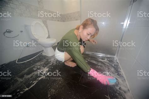 Asian Female Maid Or Housekeeper Cleaning Floor With Swab In Toilet