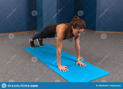 Woman In Black Sports Clothing Doing Push Up Exercise On Blue Yoga Mat