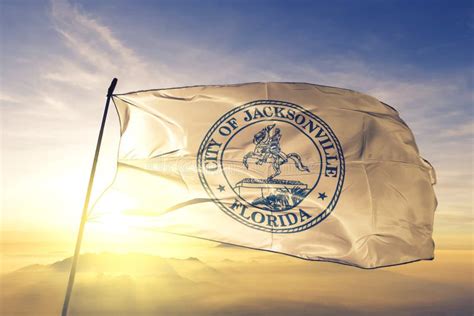 Flag Of Jacksonville Florida At Cloudy Sky Background On Sunset
