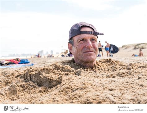 Man With Cap Sticks Head Out Of Sand On Beach A Royalty