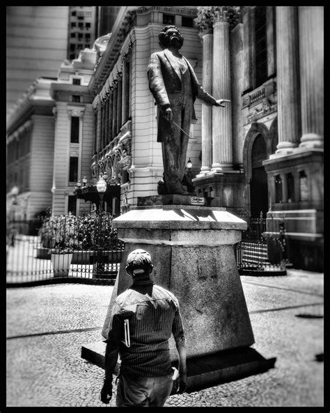 black and white photograph of a man walking past a statue