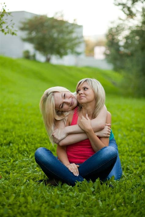 duas meninas que sentam se na grama abraçando foto de stock imagem de mulheres grama 20832492