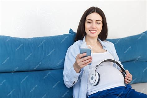 Mujer Embarazada Feliz Sosteniendo Auriculares En Su Vientre En Casa