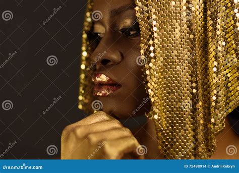 African Woman With Gold Metallic Make Up And Full Shiny Lips Looking Away Holding Chin Close Up