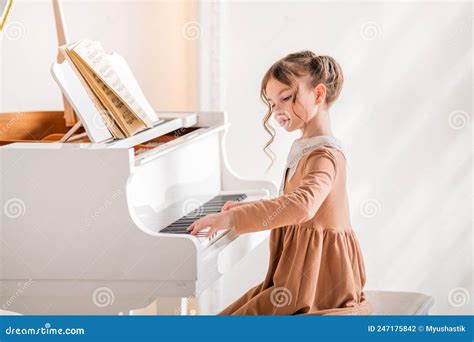A Little Girl Plays A Big White Piano In A Bright Sunny Room Stock