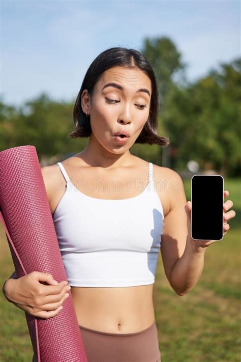 Excited Fitness Girl Recommends Application For Sport And Workout Shows Phone Screen Standing