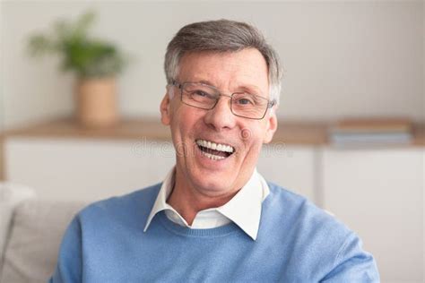 Senior Man Laughing At Camera Sitting On Couch At Home Stock Image