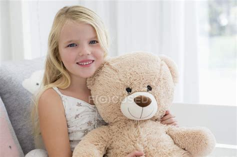 Portrait Of Cute Little Girl Holding Teddy Bear On Sofa — Caucasian