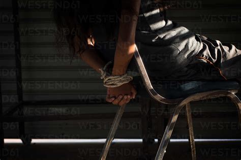 Midsection Of Woman Tied Up With Rope On Chair In Room Stock Photo