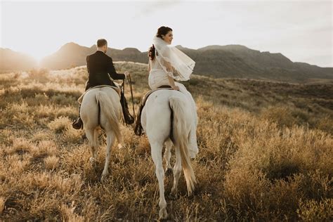 Bride And Groom Riding Horses During Sunset In West Texas