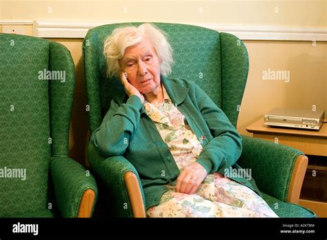 Unhappy Old Lady Aged 90 Sitting In Armchair In Nursing Home Stock