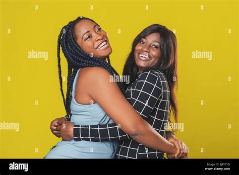 Two Beautiful Afro American Girls Hugging And Rejoicing And Smiling On Yellow Background Stock