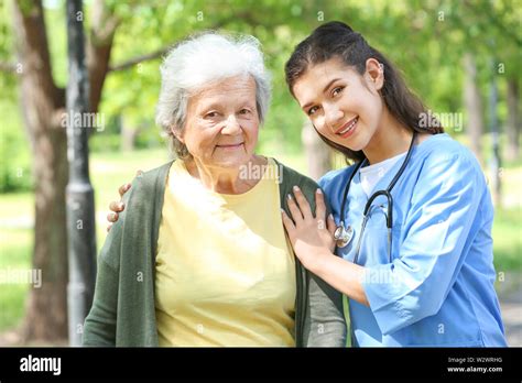Caregiver Walking With Senior Woman In Park Stock Photo Alamy