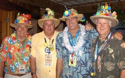 Four Men In Hawaiian Attire Posing For A Photo With One Man Wearing A