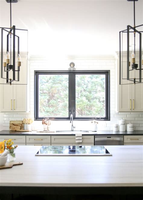 A Large Picture Window Over The Sink Lets In Natural Light That Reflects Off The Light Colored Island Countertop Both The Kitchen Sink And Faucet Are From Hausera 