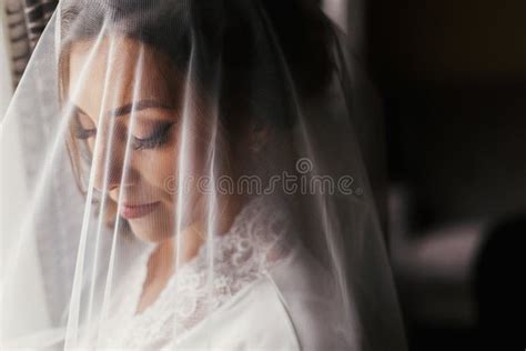 Gorgeous Beautiful Bride In Silk Robe Under Veil Posing At Window In