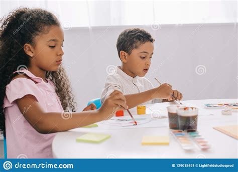 Focused African American Kids Drawing Pictures With Paints And Paint