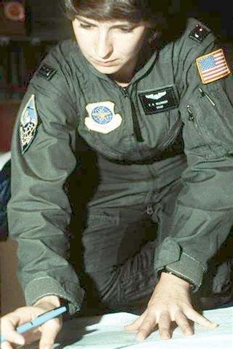 a woman in an air force uniform writing on a piece of paper with a pencil