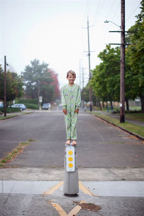 Barefoot Boy In Pajamas Stands On Top Of Concrete Pylon By Stocksy