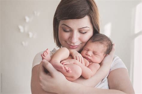 Smiling Mother Holding Her Sleeping Newborn Baby In Her Arms With Her