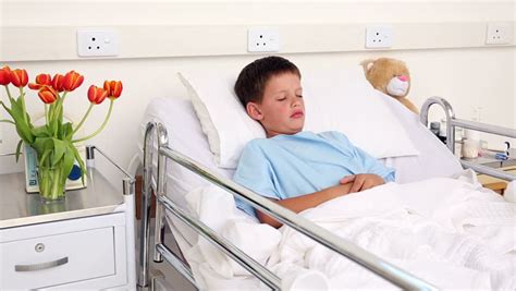 Doctor Checking The Ears Of Little Sick Boy Sitting In Bed In The