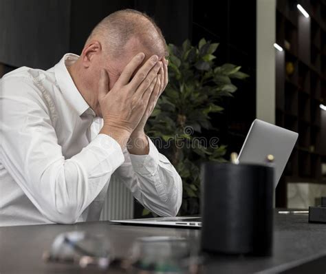Upset Tired Businessman Sitting At Office Desk With Laptop And Grabbing
