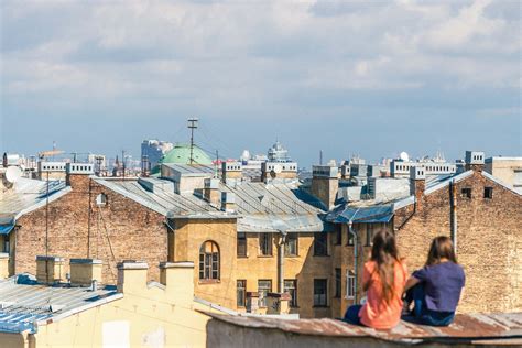 human two women sitting on roof overlooking building during daytime people Image - Free Stock Photo