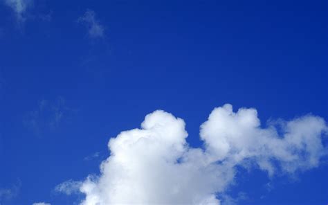 The Airplane Is Flying High In The Blue Sky With White Clouds Above It