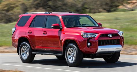 A Red Toyota Suv Driving Down The Road